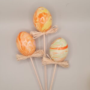 3 Orange-marmorierte Ostereier auf Stäbchen mit Bastschleife